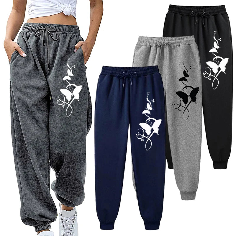 Gray, navy, and black jogger pants with butterfly designs on a white background.